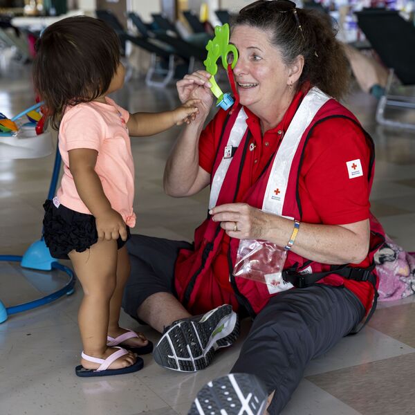 August 16, 2023. Makawao, Hawaii American Red Cross volunteer Mary McGavin plays with Jezeriah at the Hannibal Tavares Community Center in Makawao, where the Red Cross and its partners are operating shelter to help residents on Maui displaced by the historic and deadly wildfire that struck Lahaina on August 8, 2023. Photo by Scott Dalton/American Red Cross